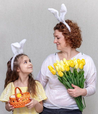 The family celebrates Easter. A woman with flowers and a girl with bunny ears and a basket of Easter...