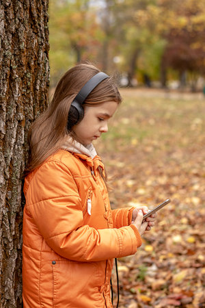 A girl listens to music on headphones in an autumn parkの写真素材