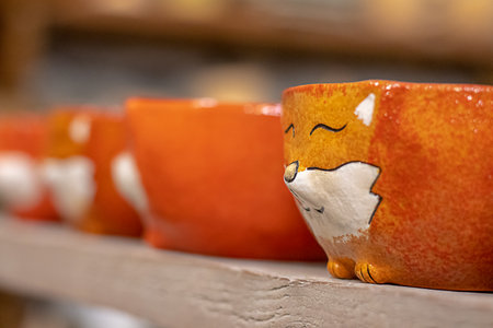 Clay ceramic cups in the shape of red fox faces. Selective focus.の写真素材