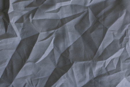 Gray wrinkled textile surface with soft shadows and natural light effectsの写真素材