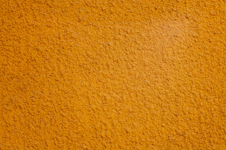 Turmeric powder texture on warm orange surface, a versatile spice for cooking and healthの写真素材
