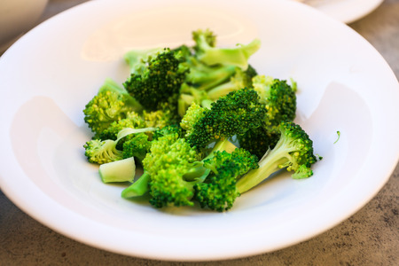 Healthy green organic raw broccoli ready for cooking close up. A bowl of cooked green broccoli....