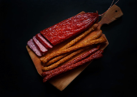 Smoked sausages on a dark background, free space for text, daylight