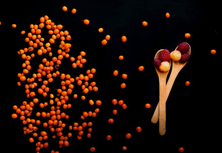 berries raspberries and sea-buckthorn on a black background, close-up, natural light, top viewの写真素材