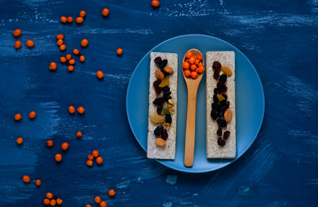 Healthy breakfast, cereal, diet bread on blue background, sea buckthorn in a wooden spoon, closeup, natural light, top viewの写真素材