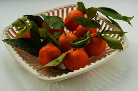 mandarins with green leaves in a white authentic fruit vaseの写真素材