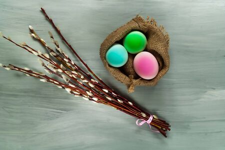 Decor for Easter holidays, a willow branch and decorative colored eggs in burlap on a concrete blue background, top viewの写真素材