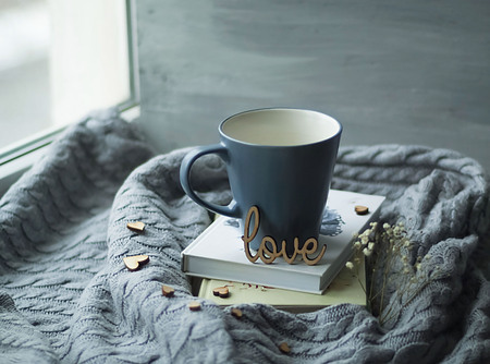Scandinavian style, a cup on a pile of books on a knitted texture on the background of a windowの写真素材