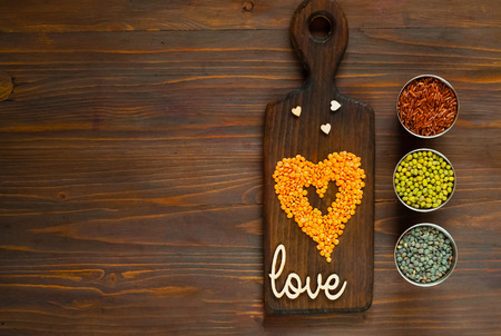 Concept of vegetarian food. Cereals and legumes with love and heart on a wooden background. Top view, empty space for textの写真素材