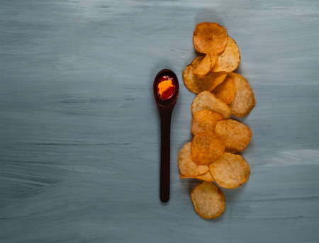 wooden spoon with ketchup and chips on a blue wooden background, top view, space for text. Convenient snackの写真素材