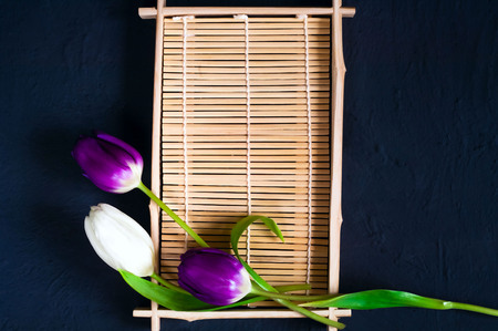 white and violet tulips on a wooden tray for sushi on a blue background of concrete, top view, space for textの写真素材