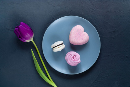 sweet dessert on a blue plate and a white tulip on a dark background, top view, space for text,holiday conceptの写真素材