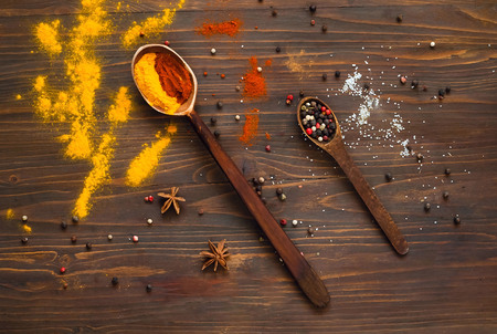 Wooden spoons and ingredients on a dark background. Background with spices, turmeric, star anise, pepper, paprika. Top view. Close up. Concept of spices for cooking, Asian cuisine, copy space,の写真素材