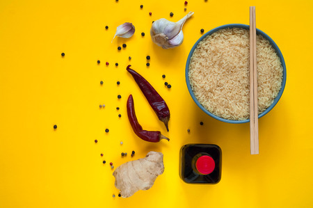 Asian food ingredients, spices and sauces on a yellow background. The concept of the most popular Chinese dishes in the world. Some types of Asian cuisine, top view, copy spaceの写真素材