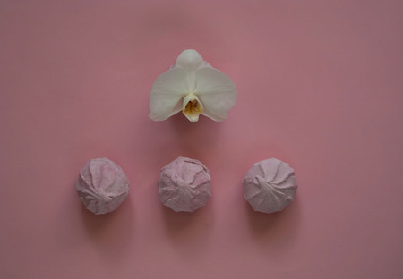 marshmallow on a gentle pink background with a white orchid flower, top view, concept of oriental sweets,copy spaceの写真素材