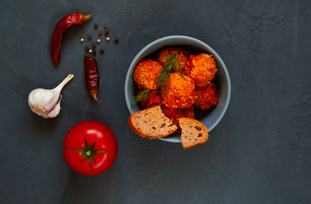dishes from minced meat in the form of balls with spices and tomato, kottbullar or fried meatballs in a blue bowl on a dark background, the concept of a traditional meat dish of Swedish cuisineの写真素材