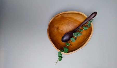 wooden bowl with a wooden spoon made of ecological natural materials, on a light background, close-up, copy space,flat lay, concept of a healthy lifestyleの写真素材