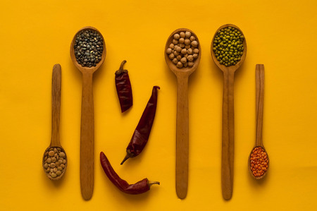 Wooden spoon and ingredients on a yellow background. The concept of cereals organic products. A healthy diet, choice of clean food, copy space, closeup.の写真素材