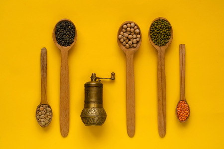 hand mill for grain,wooden spoons and ingredients on a yellow background. The concept of cereals organic products,healthy diet, choice of clean food, copy space, closeup.の写真素材