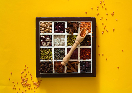 The concept of cereals organic products and spices on yellow background. Seasonings for eating,beans for cooking,healthy diet, choice of clean food, copy space, closeup,top view.の写真素材