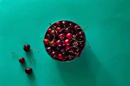 Cherry in ceramic blue bowl on background of mint color, sweet summer dish, concept of fruit. Flight lying, top view, copy space, closeupの写真素材