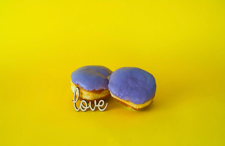 purple glazed donuts  on bright yellow background. Concept of food, colorful breakfast. Macro concept, closeup,  copy spaceの写真素材