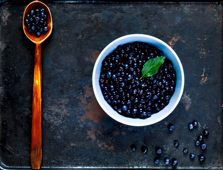 wooden spoon and bilberry in  blue bowl  on vintage rusty metal background. Berry picking, organic food concept, flat lay,copy space, closeup, bannerの写真素材