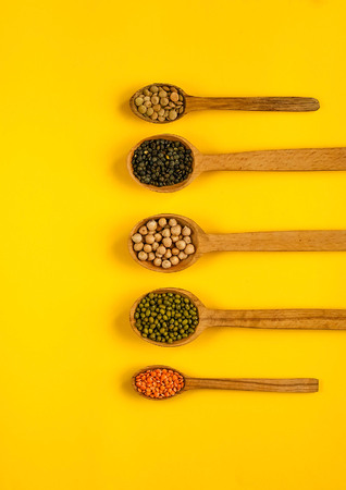 wooden spoons and ingredients on  yellow background. Various vegetarian ingredients , copy space, closeup.の写真素材