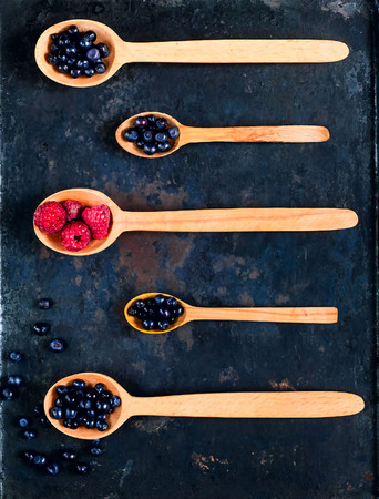 wooden spoons with assorted berries on  background of old rusty metals, concept of organic food, detoxification, clean food or vegetarian concept, copy space, closeup,の写真素材