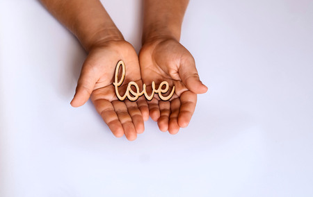 little hands of child hold in the palm of stamp the word love,copy space, closeup, flat lay, isolatedの写真素材
