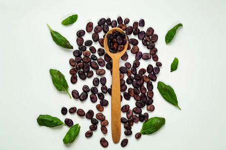 Wooden spoon with purple beans  and spinach isolated on white background. The concept of vegetarian food,  healthy diet, choice of clean food, copy space, closeupの写真素材