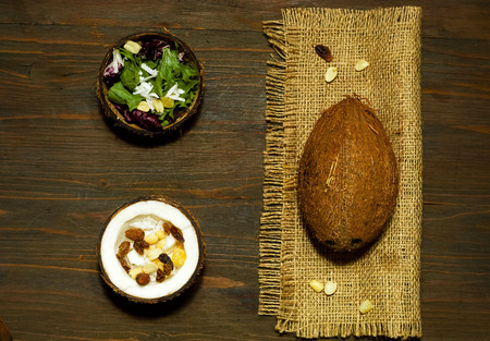 Vegetarian salad with coconut shavings and nuts. Salmon Poke Salad in coconut bowl on the texture of...