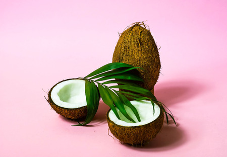 Tropical fruit whole and halves of coconut.Creative layout made of coconuts and leaves on pink background.. Food concept. Copy space, closeupの写真素材