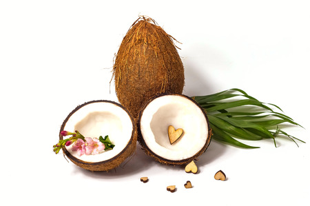 Creative layout of coconuts with wooden hearts and a delicate pink flower, concept of holiday. Copy...
