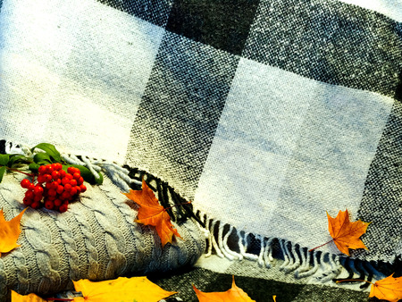 Autumn home decor amid bright yellow leaves on the background of knitted clothes and checkered plaid. Hygge Style, concept of comfort and coziness.Copy space. Close upの写真素材