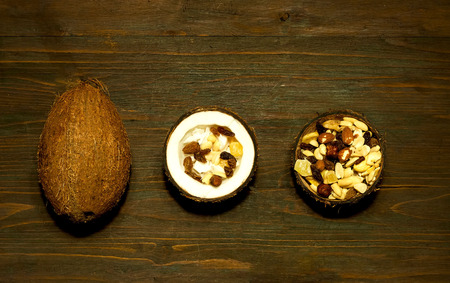 Vegetarian salad with coconut shavings and nuts in coconut bowl on wooden background. The concept of...