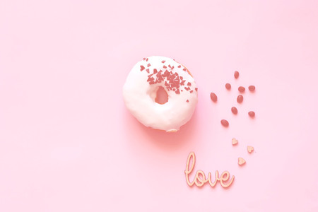 White glazed donut  with black chocolate sweets on colar background. Flat lay. Food concept, colorful breakfast. Color of 2019. Close up, copy space.の写真素材