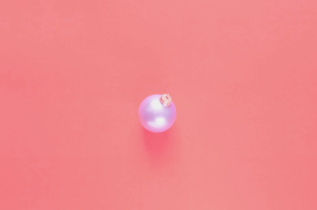 Christmas ball on coral background. Color of the year 2019 concept. Copy space, closeup, minimalism