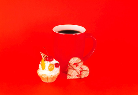 Big red cup of coffee and cupcake with cherry on backgroundの写真素材