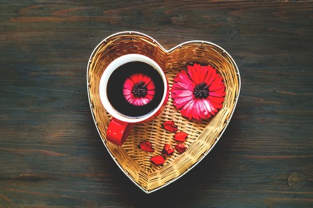 Valentines day greeting postcard. Big red cup of coffee with flower in heart shaped basket on wooden...