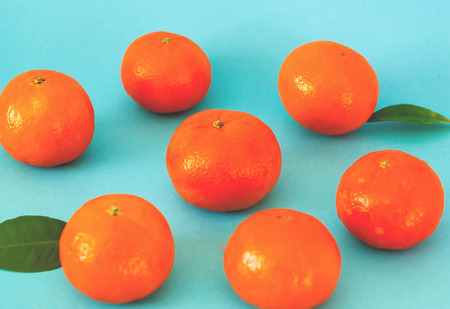 Pattern of orange mandarins on blue background. Copy space. Closeup, top view.
