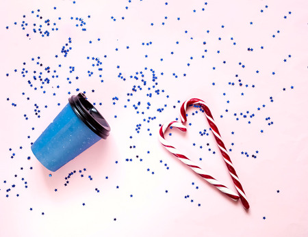 Coffee in disposable paper cups and Caramel heart on pink pastel trendy background. Festive backdrop for projects. Flat lay, close up. Top view, copy space.の写真素材
