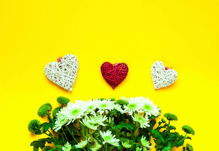 Chrysanthemums and decorative hearts on yellow background. Festive decor. Copy space Close-up, top view.の写真素材