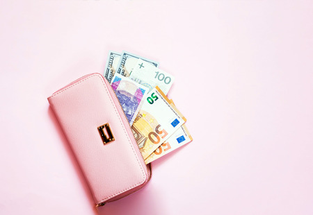 Pink purse with euro and dollar banknotes on pink background.Closeup, copy space.の写真素材