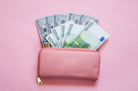 Pink purse with euro and dollar on pink background.Closeup, copy space.の写真素材