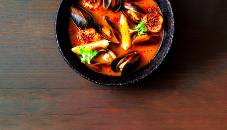 Mussels with sauce in authentic frying pan on wooden background.The concept of  healthy and satisfying appetizer or light meal.Closeup, copy space.の写真素材
