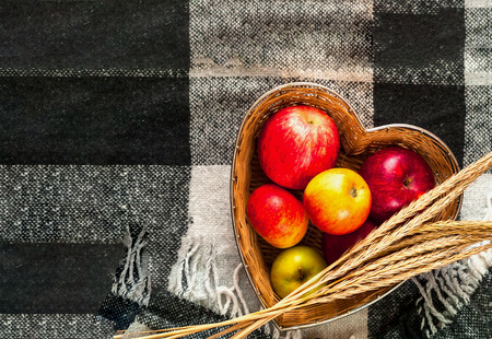 Red apples in straw vase on Checkered Plaid. Concept of comfort and coziness.Closeup, copy space.の写真素材