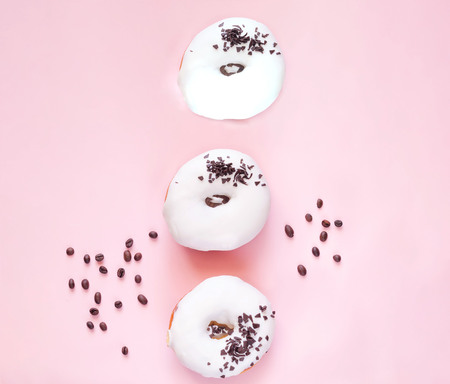 White glazed donut  with black chocolate sweets on pink background. Close up, copy space.の写真素材