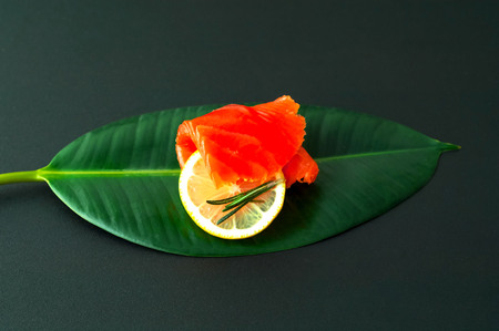 Salmon fillet on tropical leaf on dark background.の写真素材