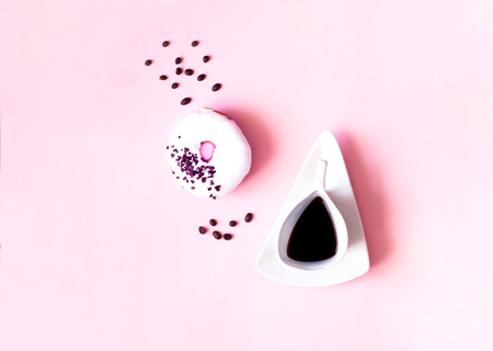 Colorful breakfast. Cup of coffee and white glazed donut on pastel pink background.の写真素材